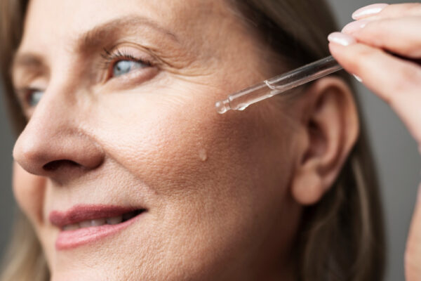 Femeie matură aplicând ser facial cu pipetă